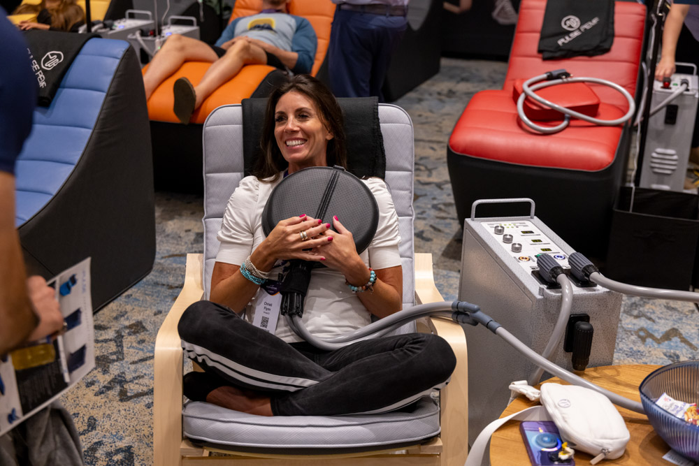 woman smiling while seated in a chair trying out Biology & Longevity tech